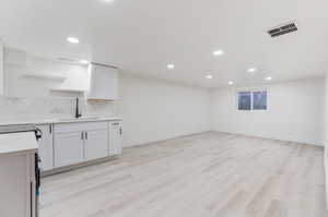 Basement featuring sink and light hardwood / wood-style floors