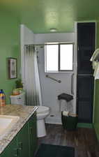 Bathroom featuring vanity, hardwood / wood-style floors, curtained shower, toilet, and a textured ceiling