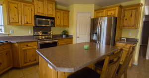 Kitchen featuring appliances with stainless steel finishes, light tile patterned floors, and a kitchen island