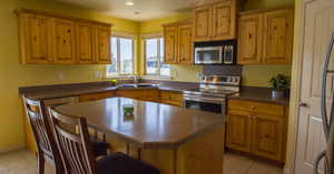 Kitchen featuring sink, appliances with stainless steel finishes, a center island, and light tile patterned floors