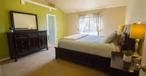 Primary Bedroom with light colored carpet and vaulted ceiling