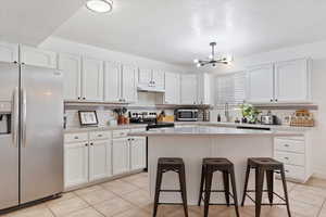 Kitchen with white cabinetry, a center island, backsplash, and appliances with stainless steel finishes