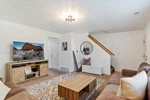 Carpeted living room with a textured ceiling