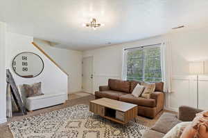 Carpeted living room featuring a notable chandelier and a textured ceiling