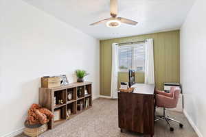 Carpeted home office featuring ceiling fan