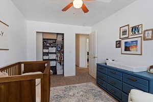 Bedroom with carpet floors, ceiling fan, a closet, and a nursery area