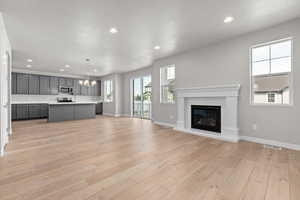 Unfurnished living room featuring a notable chandelier, a textured ceiling, and light hardwood / wood-style floors