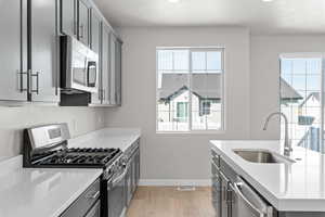 Kitchen with appliances with stainless steel finishes, light hardwood / wood-style flooring, a textured ceiling, and sink