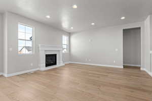 Unfurnished living room with plenty of natural light, light wood-type flooring, and a textured ceiling