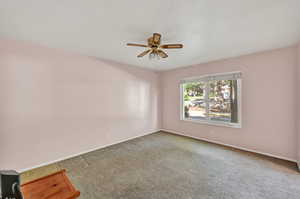 Unfurnished room featuring carpet floors and ceiling fan