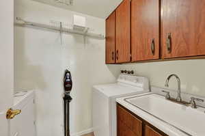 Laundry area featuring sink, washer and dryer, and cabinets