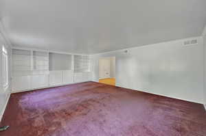 Carpeted spare room featuring ornamental molding and built in shelves