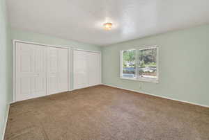 Unfurnished bedroom featuring two closets and carpet floors