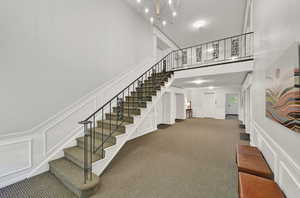 Staircase featuring an inviting chandelier, carpet floors, and a towering ceiling