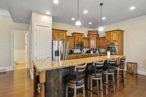 Kitchen featuring hardwood / wood-style flooring, stainless steel appliances, a kitchen breakfast bar, and a large island with sink