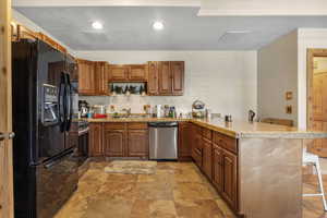 Kitchen with light tile patterned flooring, kitchen peninsula, stainless steel appliances, a kitchen breakfast bar, and sink