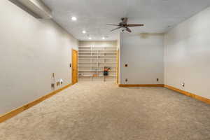 Basement with carpet floors, a textured ceiling, and ceiling fan