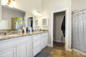 Bathroom featuring double vanity, tile patterned flooring, a tile shower, and toilet