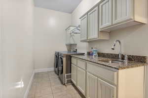 Laundry area featuring sink, cabinets, independent washer and dryer, and light tile patterned flooring