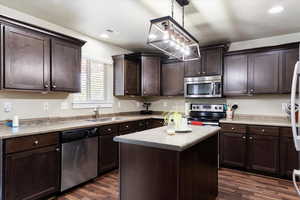 Kitchen featuring stainless steel appliances, dark brown cabinetry, sink, and dark wood-type flooring