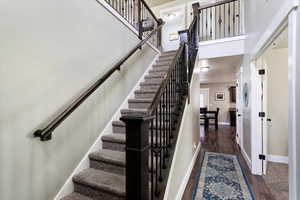 Stairs with dark hardwood / wood-style flooring and a high ceiling