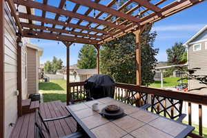 Deck featuring area for grilling, a fire pit, a lawn, and a pergola