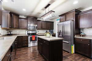 Kitchen with hanging light fixtures, appliances with stainless steel finishes, sink, and dark wood-type flooring