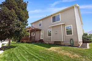 Back of house featuring a pergola, a deck, and a lawn