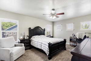 Bedroom with light carpet, multiple windows, and ceiling fan