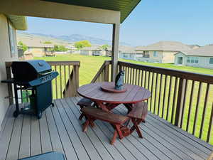 Wooden terrace with a yard, an outdoor structure, a mountain view, and a grill