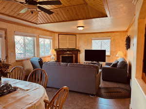 Tiled living room featuring ceiling fan, crown molding, and wood ceiling