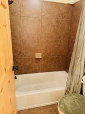 Bathroom with tile patterned floors, shower / tub combo with curtain, and toilet