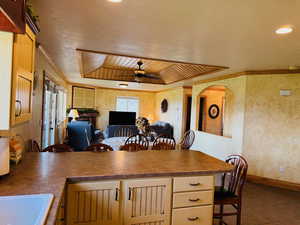 Kitchen with crown molding, wood ceiling, ceiling fan, a tray ceiling, and tile patterned flooring