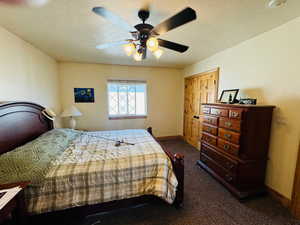 Ensuite bedroom featuring ceiling fan, a closet, a textured ceiling, and carpet