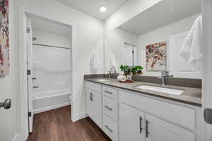 Bathroom featuring vanity, wood-type flooring, a textured ceiling, and shower / washtub combination