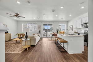 Living room featuring ceiling fan, sink, dark wood-type flooring, and a textured ceiling