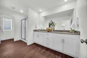 Bathroom with a textured ceiling, vanity, wood-type flooring, and a shower with door