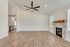 Unfurnished living room featuring light hardwood / wood-style flooring, ceiling fan, and lofted ceiling