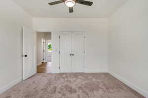 Unfurnished bedroom with light carpet, a closet, and ceiling fan