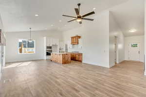 Kitchen featuring white microwave, oven, light hardwood / wood-style flooring, and a center island with sink