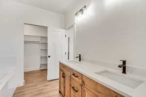 Bathroom featuring a bath, wood-type flooring, and dual bowl vanity