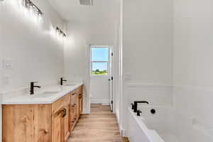 Bathroom with toilet, a bathing tub, hardwood / wood-style floors, and dual bowl vanity