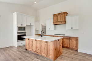 Kitchen featuring appliances with stainless steel finishes, a center island with sink, sink, light hardwood / wood-style floors, and white cabinetry