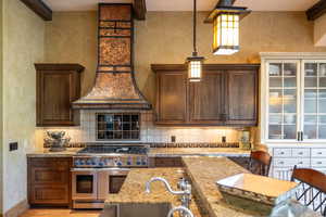 Kitchen featuring double oven range, light stone counters, decorative light fixtures, dark brown cabinetry, and light wood-type flooring