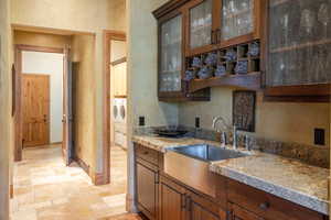 Kitchen featuring washer and clothes dryer, sink, light stone counters, and light tile patterned floors