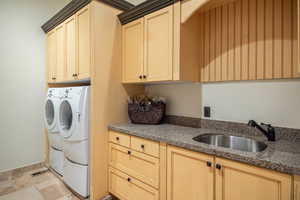 Laundry area with sink, cabinets, washing machine and dryer, and light tile patterned floors