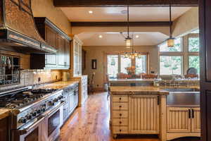 Kitchen featuring light hardwood / wood-style floors, range with two ovens, a wealth of natural light, and custom range hood