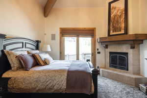 Primary Owners Suite - Bedroom with beam ceiling, carpet, a tile fireplace, and access to outside