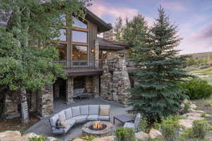 Back house at dusk with a patio area and an outdoor living space with a fire pit