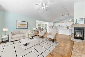 Living room with light hardwood / wood-style floors, ceiling fan, and vaulted ceiling